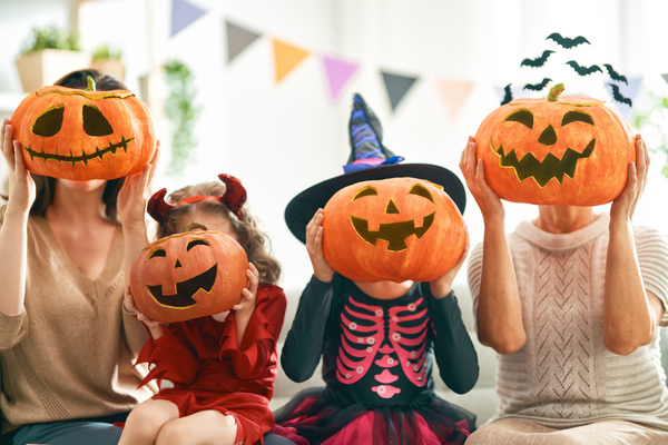 Children in Fancy Dress holding carved pumpkins over their faces.