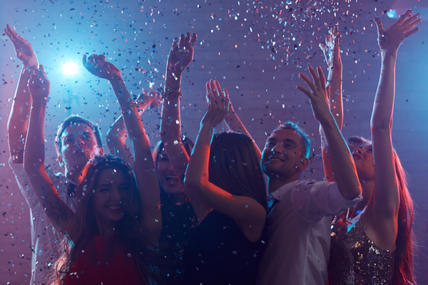 People celebrating the new year, dancing surrounded by lights and confetti
